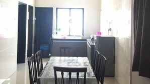 Ein Essbereich mit Tisch und Stühlen, ein Fenster und im Hintergrund eine Küche.