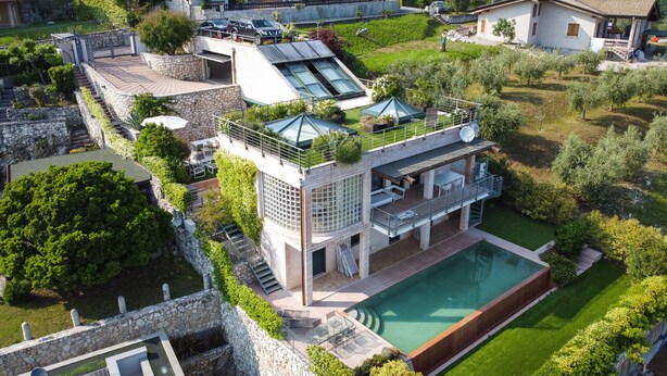Een modern huis met een ruime glazen conservatorium, een zwembad en een verzorgde tuin.