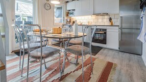 Eine moderne Küche mit Esstisch, Stühlen, einem Kühlschrank und einer Mikrowelle.