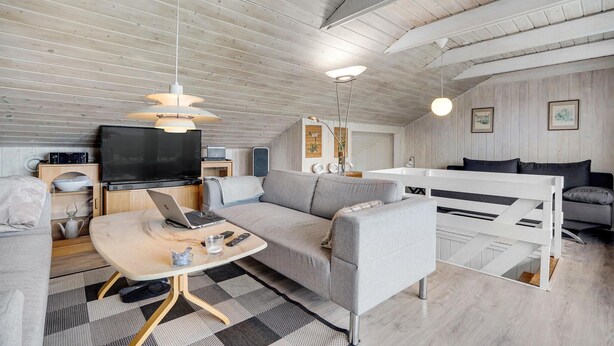 Ein modernes, helles Wohnzimmer mit Sofa, Couchtisch und Fernseher.