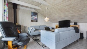 Ein gemütliches Wohnzimmer mit Kamin, einer Couch, einem Ledersessel und einem Fernseher.