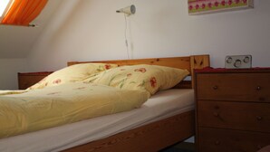 A bedroom with a wooden bed, a bedside table with a radio, and a wall-mounted heater. - Ferienwohnungen Hees (Emmerzhausen)