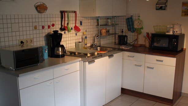 A kitchen with white cabinets, a dishwasher, a toaster, a sink, and a microwave. - Ferienwohnungen Hees (Emmerzhausen)