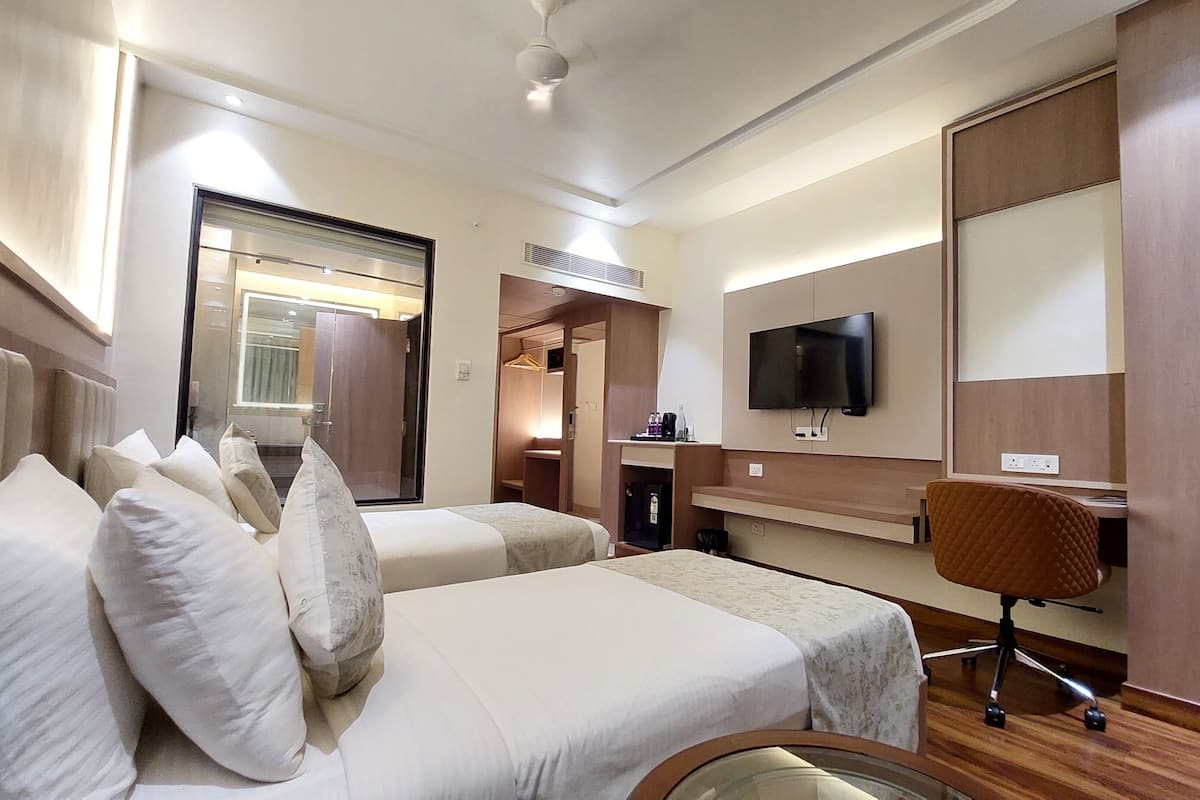 A hotel room with two beds, a TV, a desk, and a wardrobe.