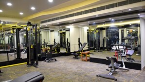Una palestra con diverse attrezzature per esercizi, specchi e pavimento rivestito di moquette.