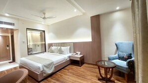Una camera d'albergo con un letto, un comodino, una sedia e un tavolino con piano in vetro.