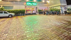 Un hotel con il cartello 'City Inn', diversi piani e un'area d'ingresso pavimentata con motociclette parcheggiate.