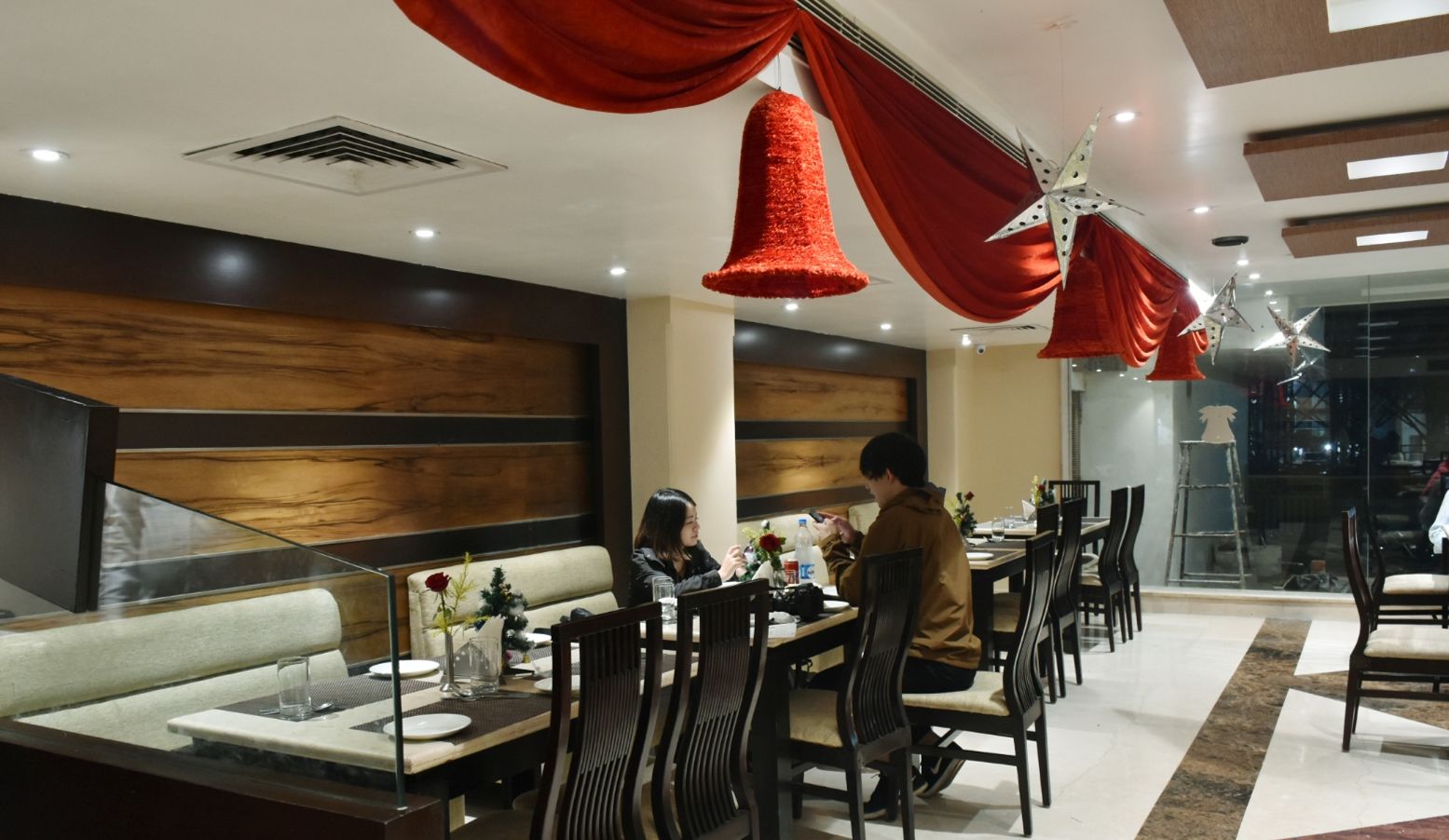 A restaurant with booths and tables, red hanging decorations, and a modern interior design.