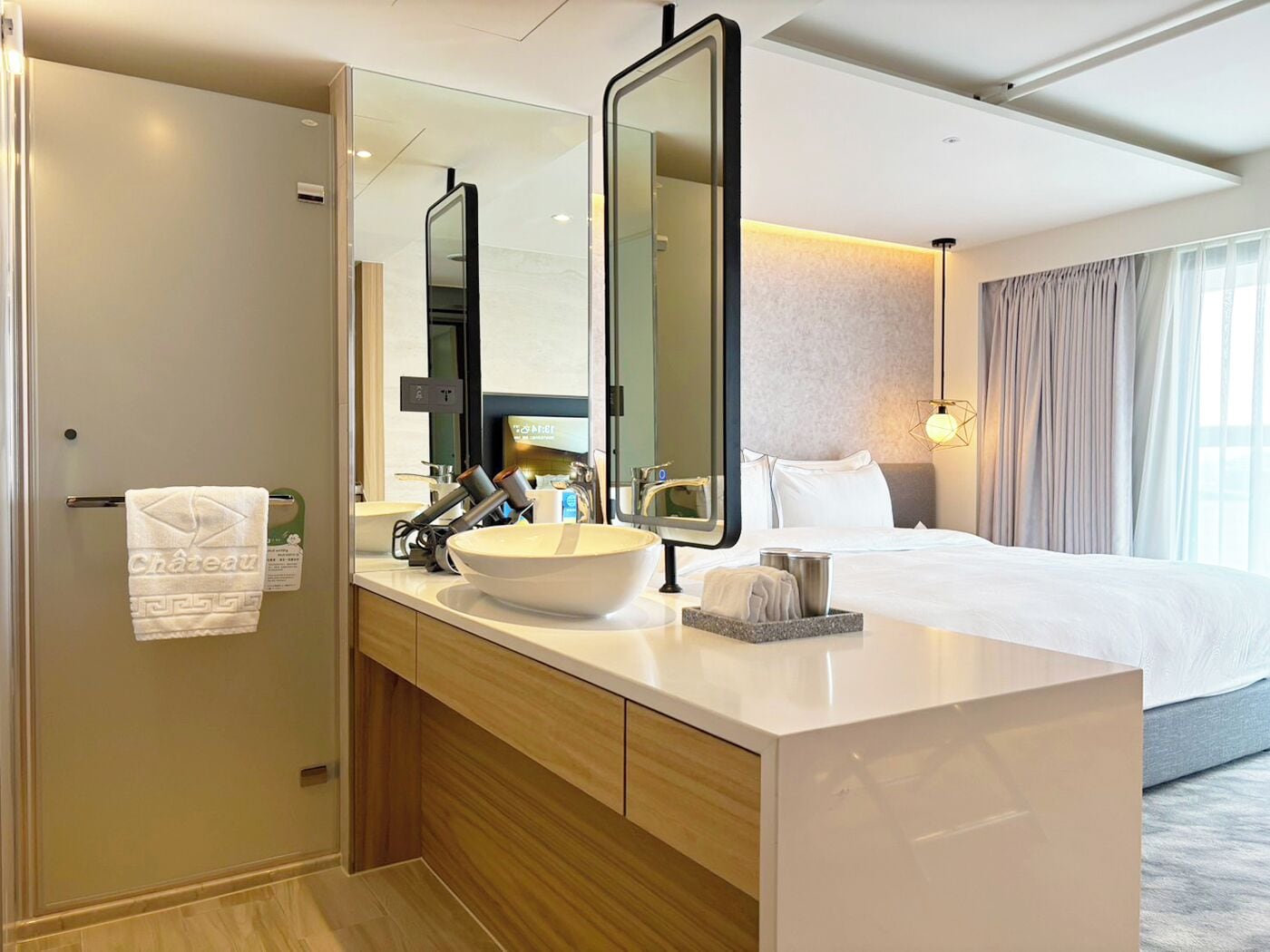 A hotel bathroom with a large mirror, a sink, a towel rack, and a shower area.