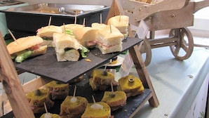 Una mesa de buffet con sándwiches y pequeñas bollerías.
