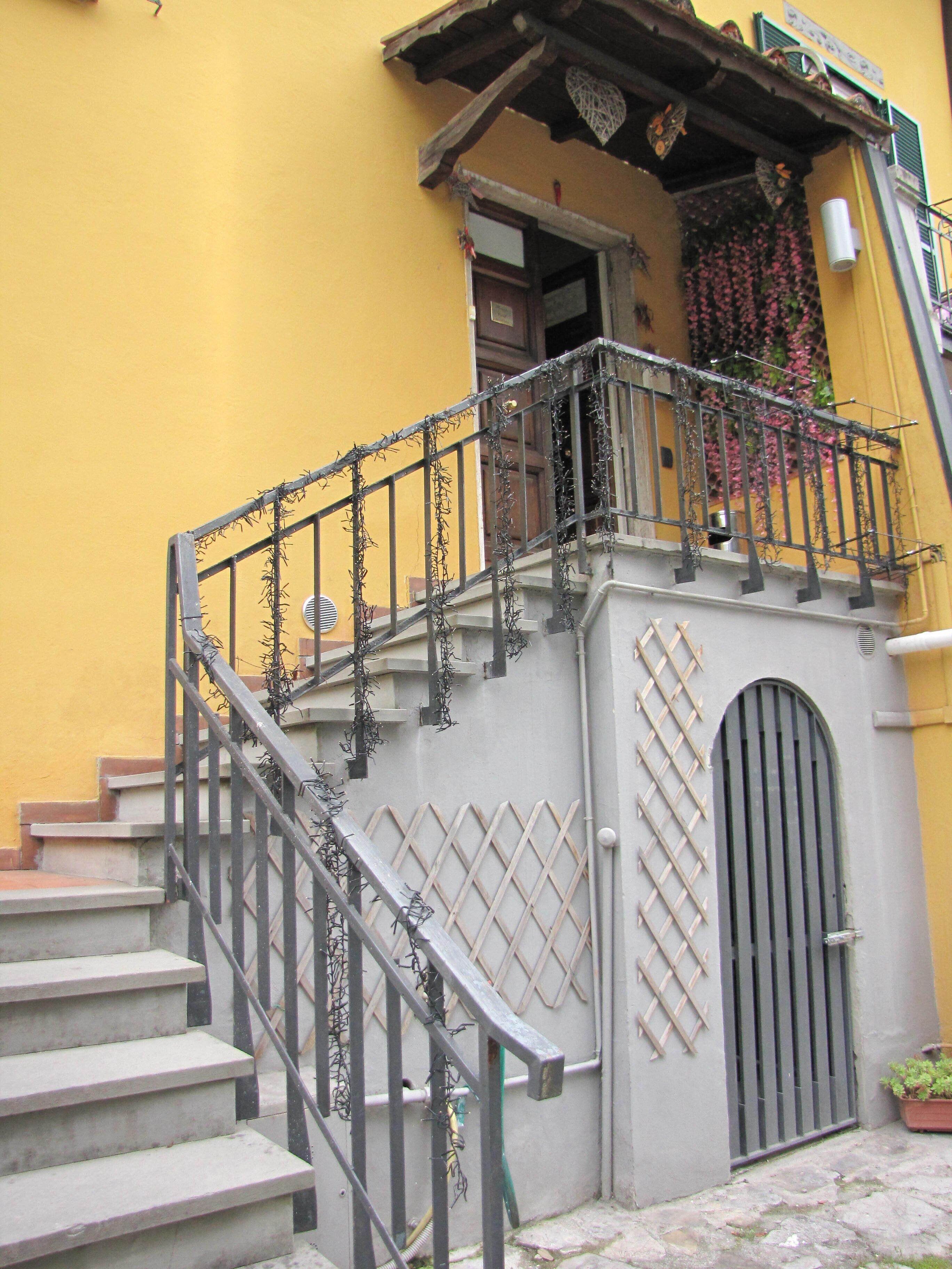 A staircase with a metal railing, a wooden door, and a small balcony with flowers.