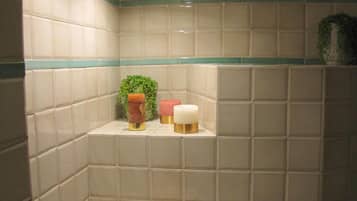 Bathroom features a shelf with a potted plant, candles, and a decorative container.