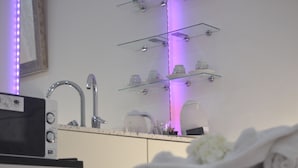 Baño con lavamanos, espejo y repisas con artículos de aseo.