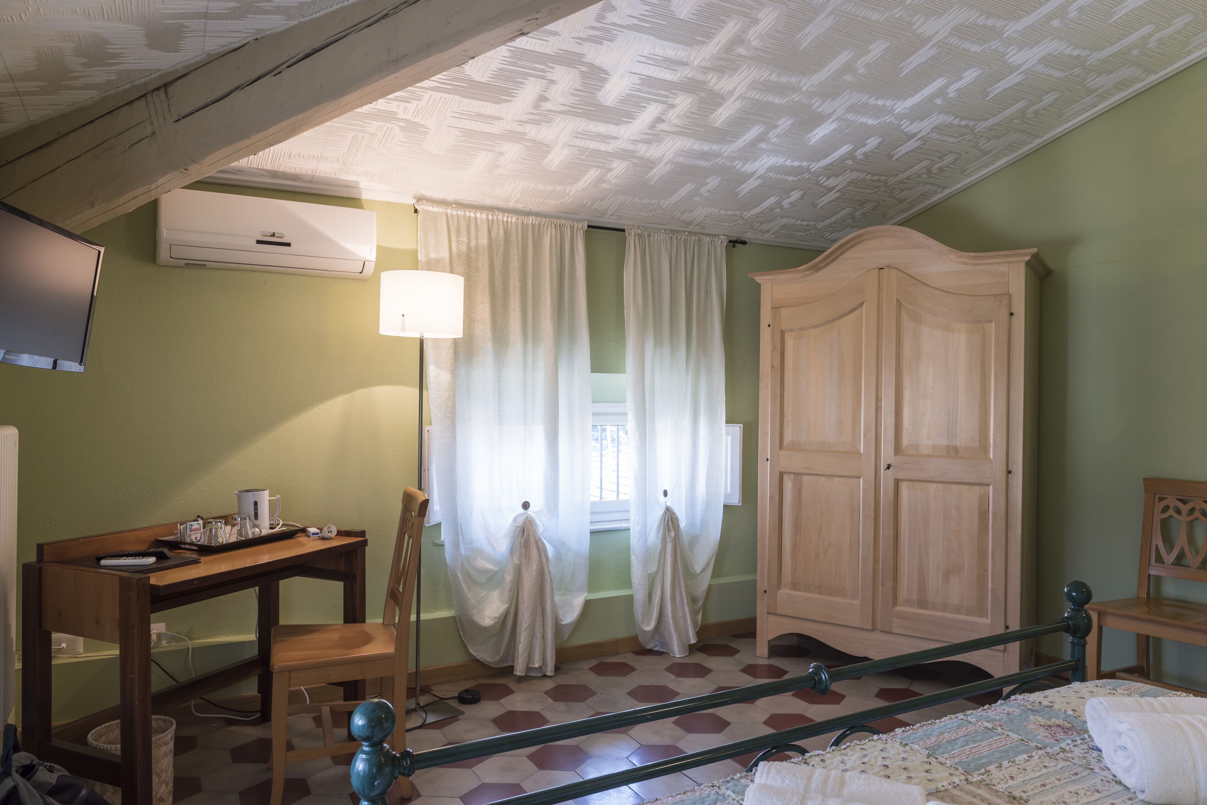 Una habitación con una cama, un escritorio de madera, una silla, un armario y un televisor.