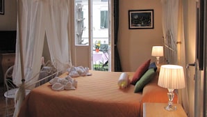 Habitación de hotel con cama, mesita de noche con lámpara, ventana con vista al exterior y puerta.