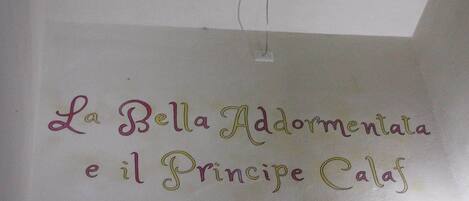 A wall with the text "La Bella Addomentata e il Principe Calaf" in cursive writing.