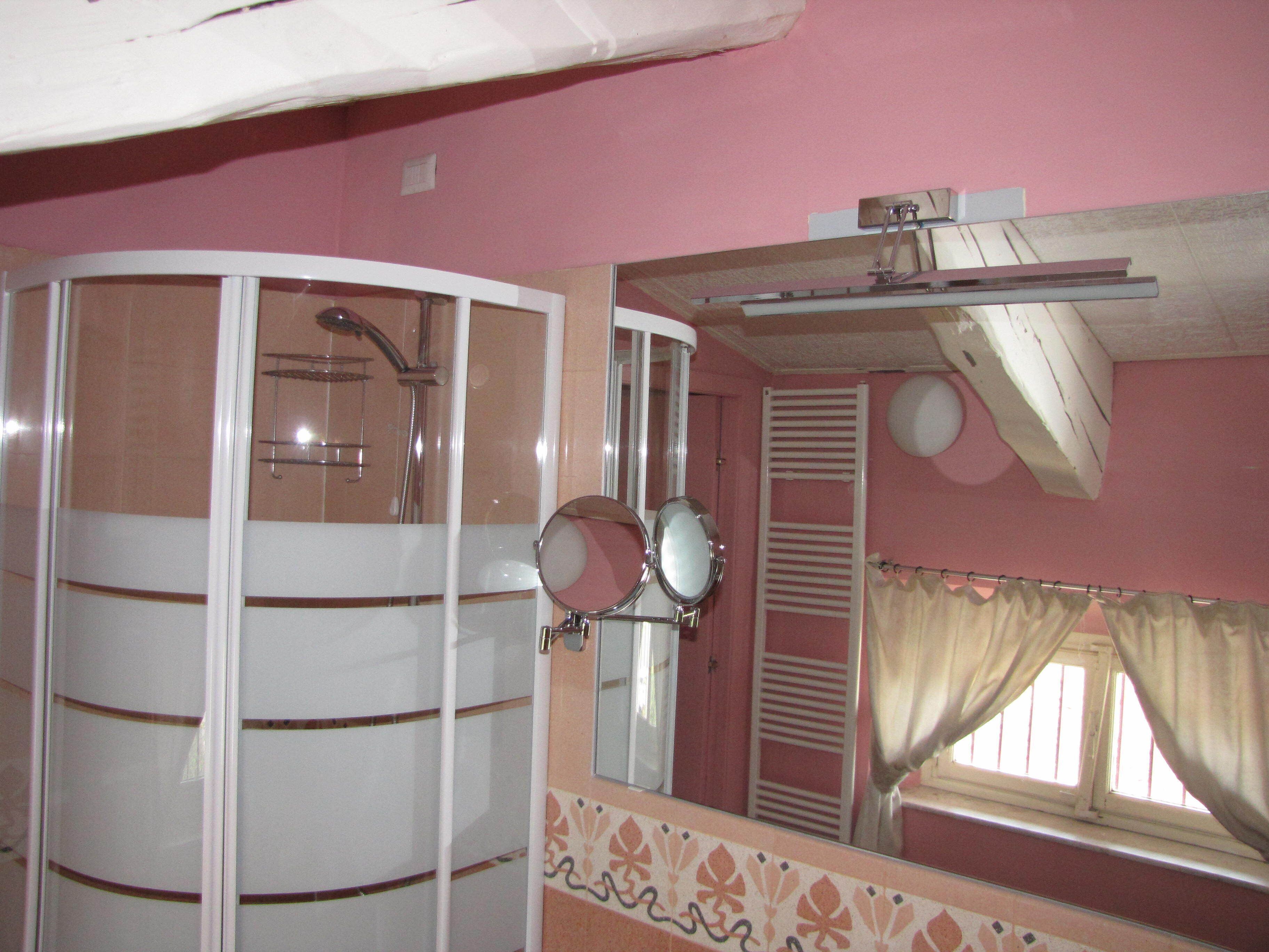 Baño con ducha, espejo y ventana con cortinas.