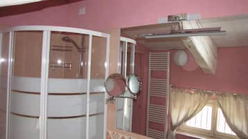 Ein Badezimmer mit Dusche, Spiegel und einem fensterbelaubten Fenster.
