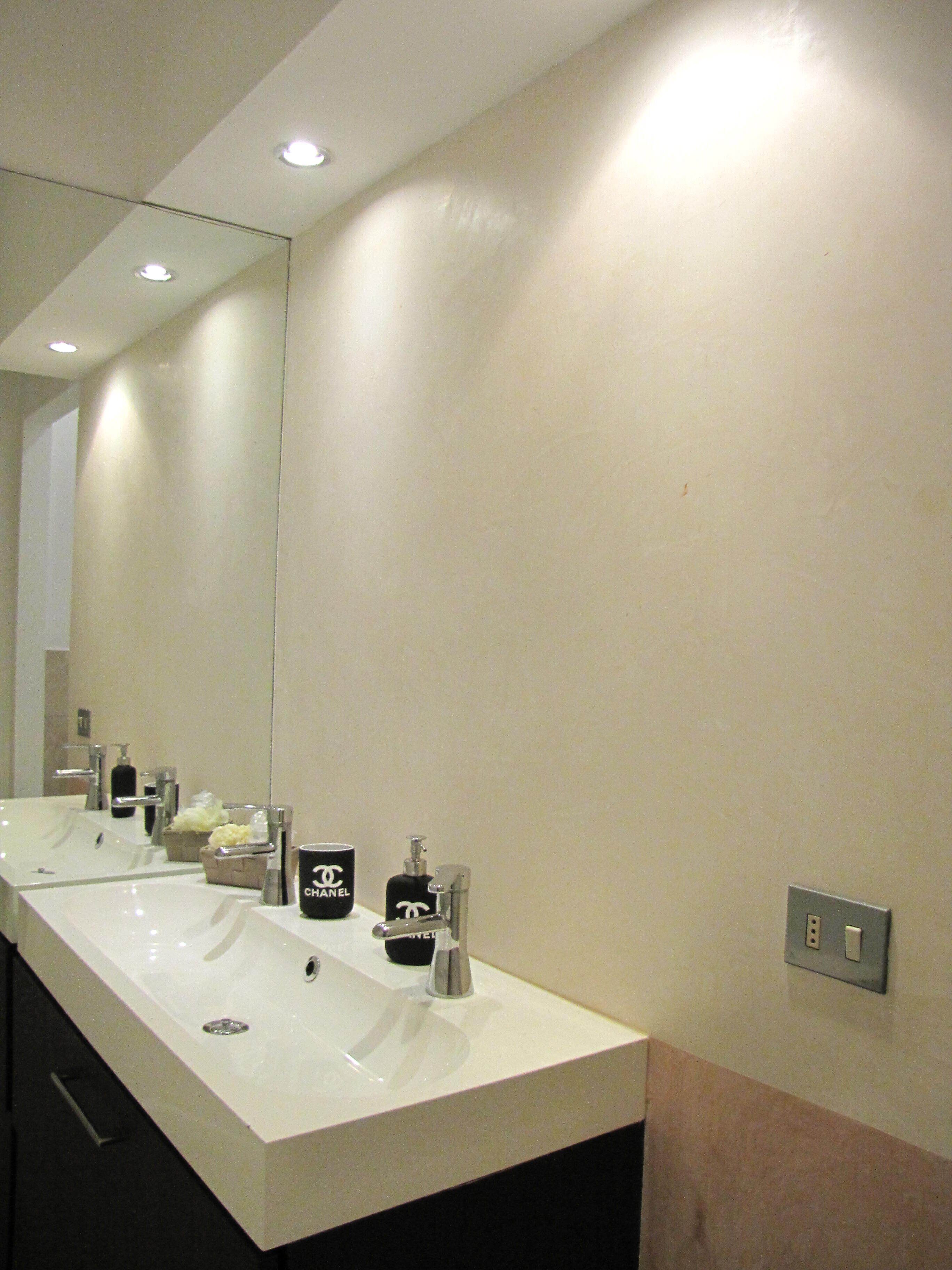 Une salle de bain avec deux lavabos, un grand miroir et un luminaire fixé au mur.
