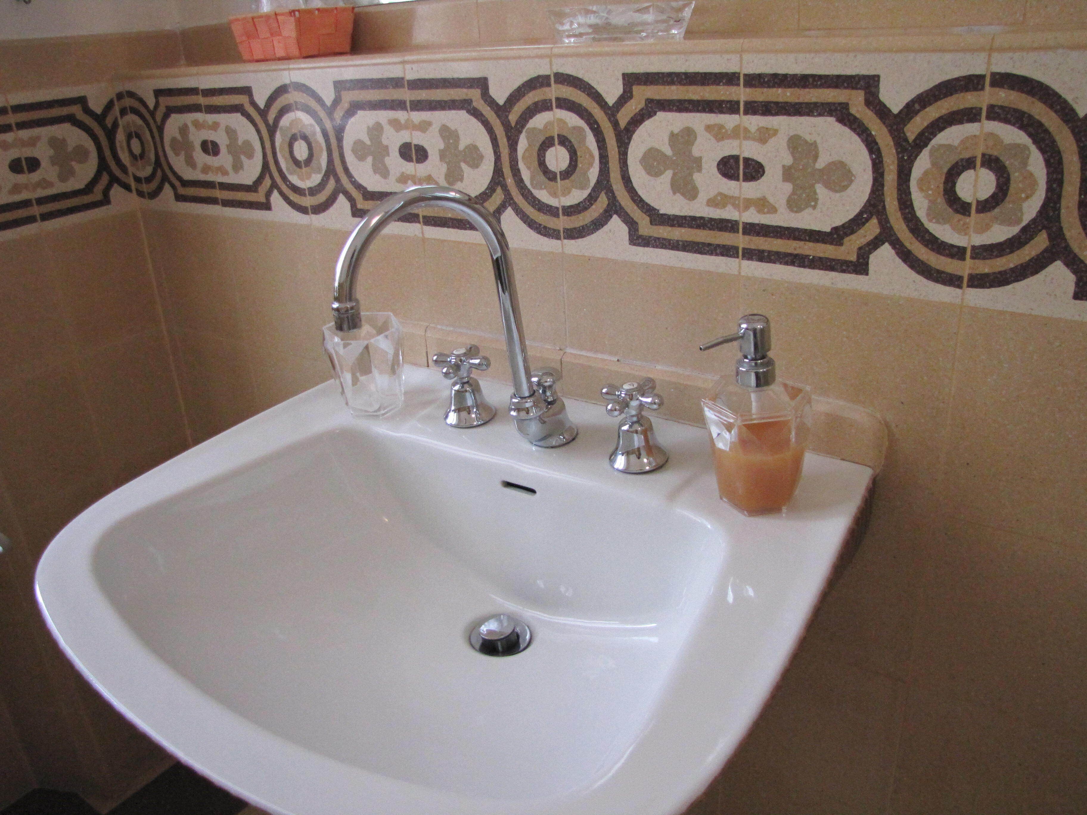 Un lavabo de bany amb un sol vàter, un dispensador de sabó i un plat de sabó de vidre.