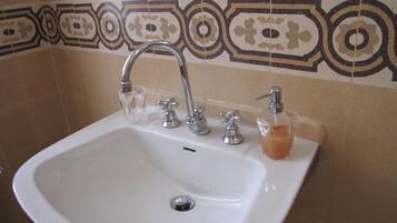 Un lavabo de bany amb un sol vàter, un dispensador de sabó i un plat de sabó de vidre.