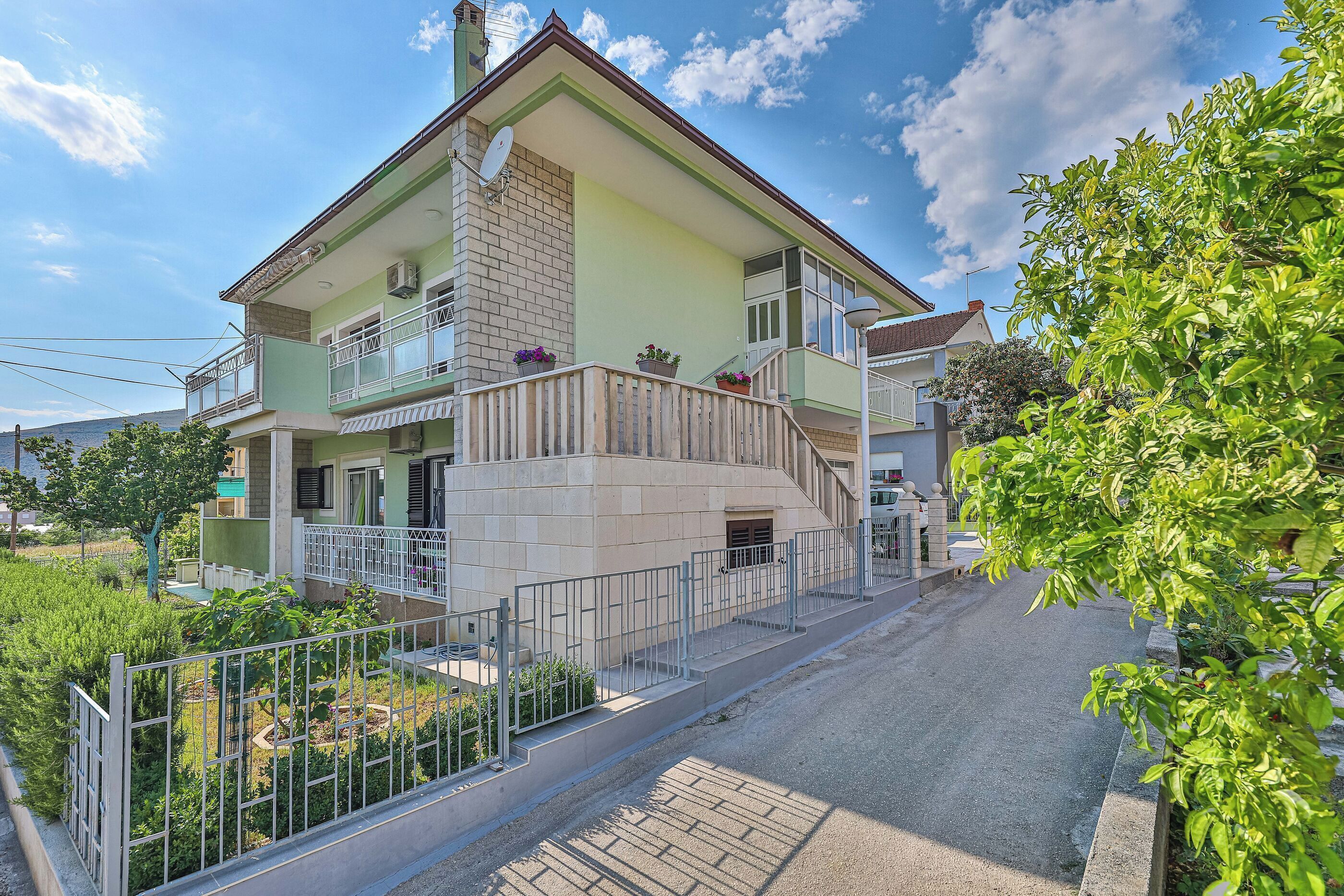A two-story house with a balcony, a satellite dish, and a paved driveway.