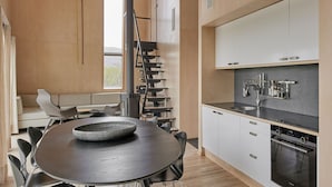 Une cuisine moderne dotée d’une cuisinière intégrée, de meubles blancs et d’un plan de travail noir.