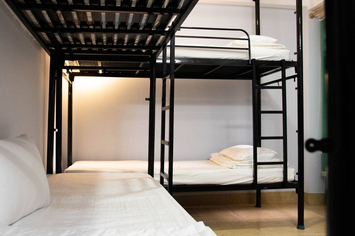 Quarto com beliche e uma cama de solteiro à esquerda.