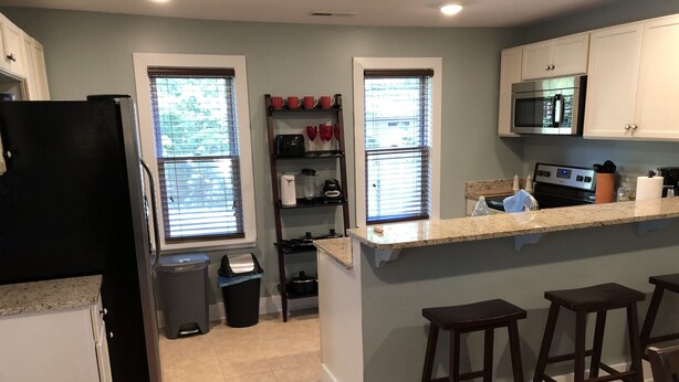 A kitchen with a central island, bar stools, a microwave, and a stove. - Nana's Cottage 3 miles from downtown, pet friendly (Asheville)