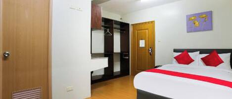 A bedroom with a bed, a wardrobe, a mirror, and a door.