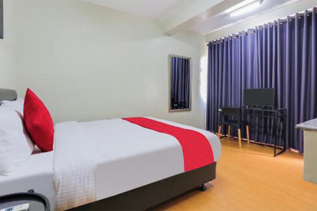 Une chambre d’hôtel avec un lit, un bureau et une télévision.