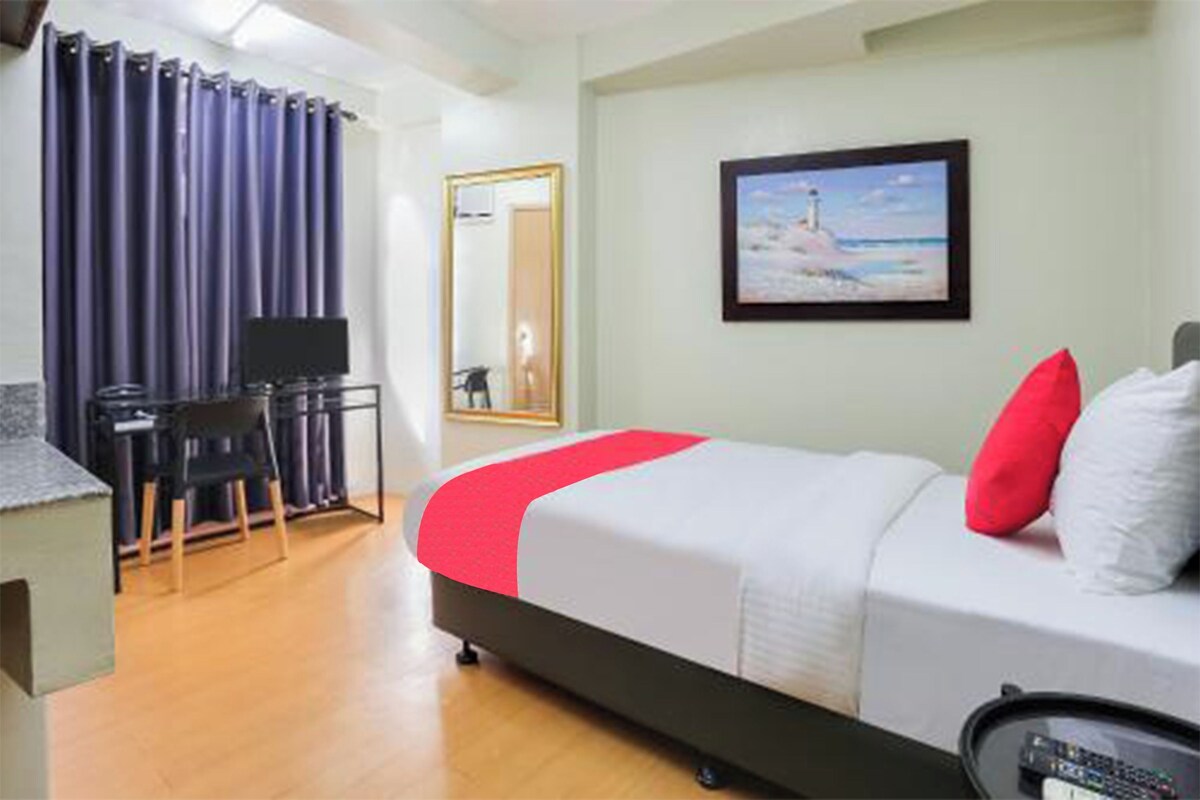 Une chambre d’hôtel avec un lit, un bureau, une chaise, une télévision et un tableau au mur.