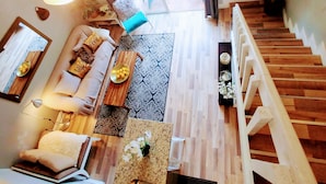 Een ruime woonkamer met een houten trap, een zithoek, een eettafel en uitzicht op het terras.