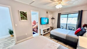 Hotelkamer met een bed, een televisie, een plafondventilator en uitzicht op de omgeving.