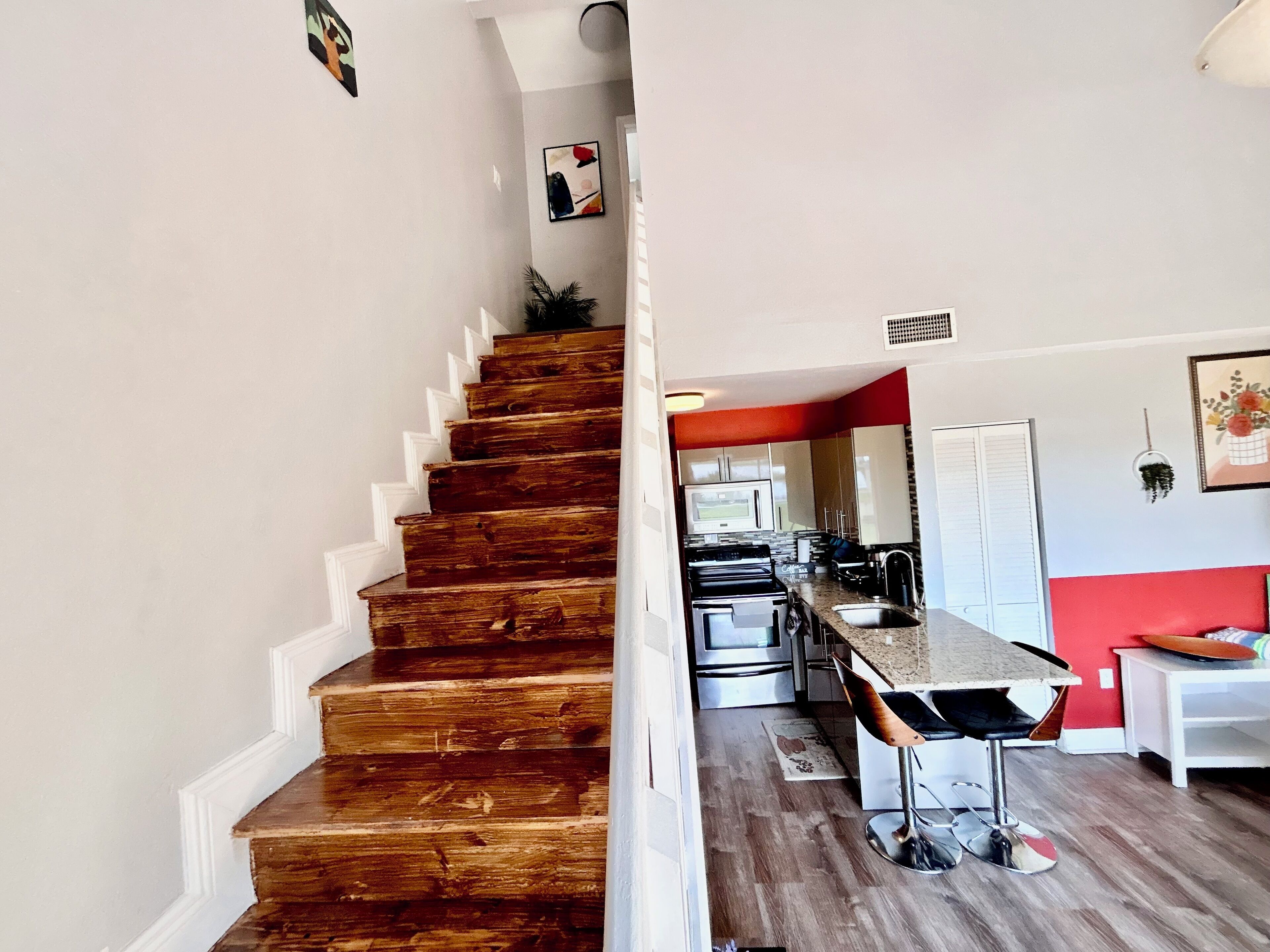 Un escalier menant à une cuisine équipée d’appareils électroménagers modernes et dotée d’un coin bar.