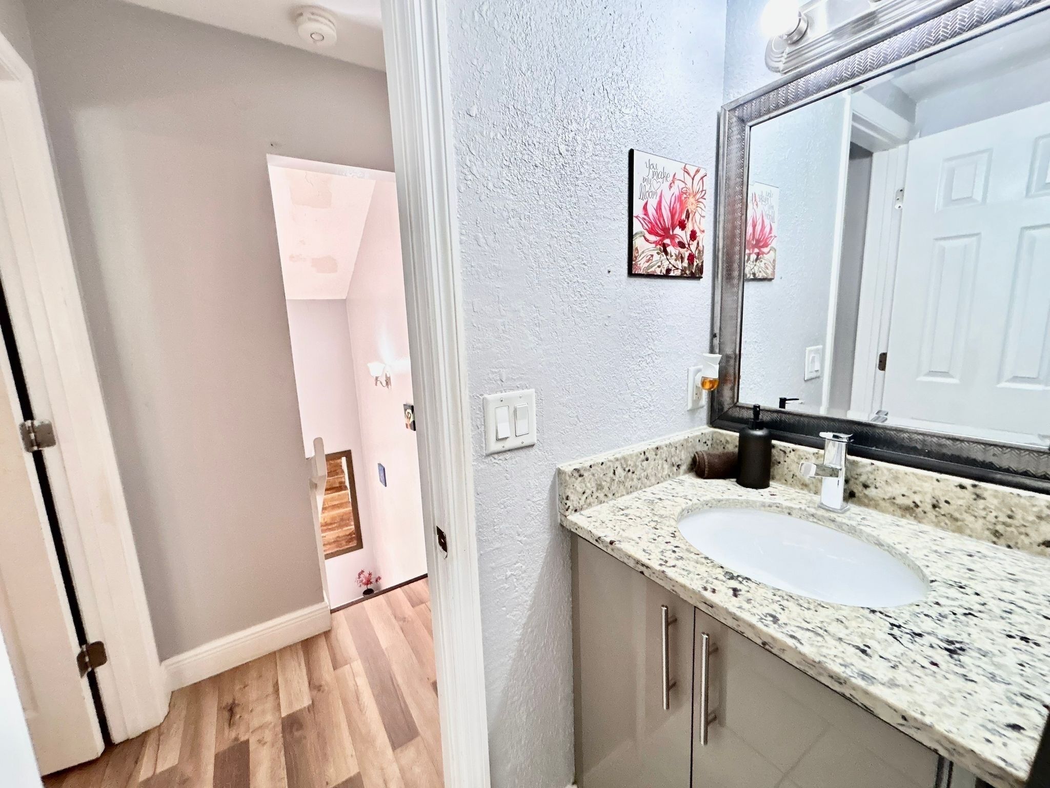 A bathroom with a granite countertop, a white sink, and a large mirror.
