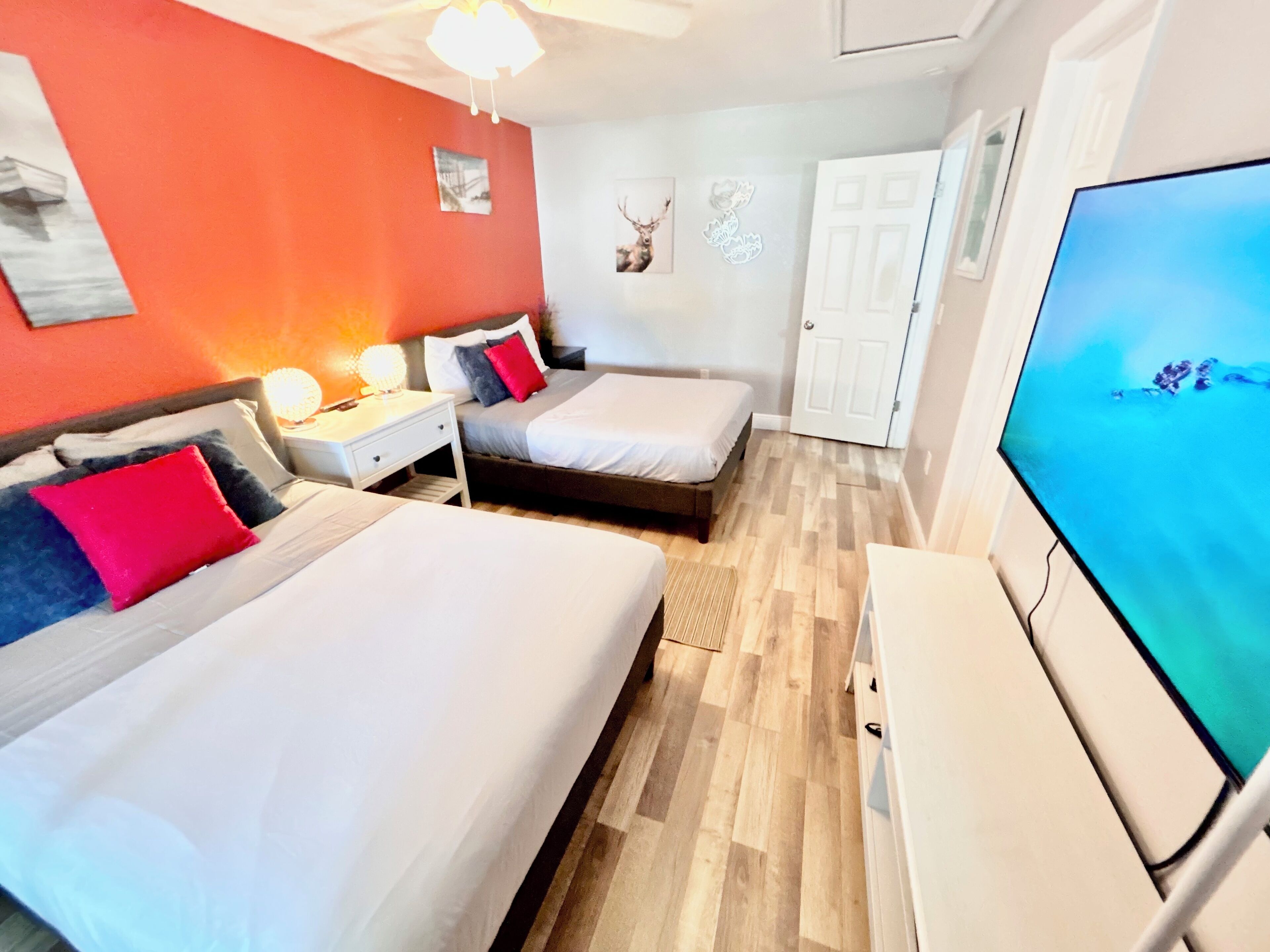 A hotel room with two beds, a TV, and a door.
