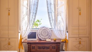 A bedroom with two beds, a wooden dresser, a window with curtains, and a decorative wall hanging. - Solemar Sicilia - Casa Porto Bagnera (Santa Flavia)