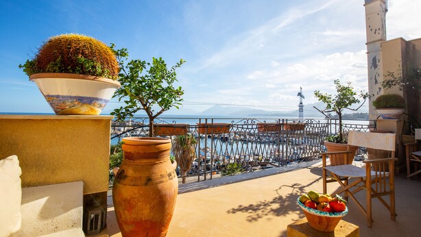 A terrace with a view of the sea, potted plants, and outdoor furniture. - Solemar Sicilia - Casa Porto Bagnera (Santa Flavia)