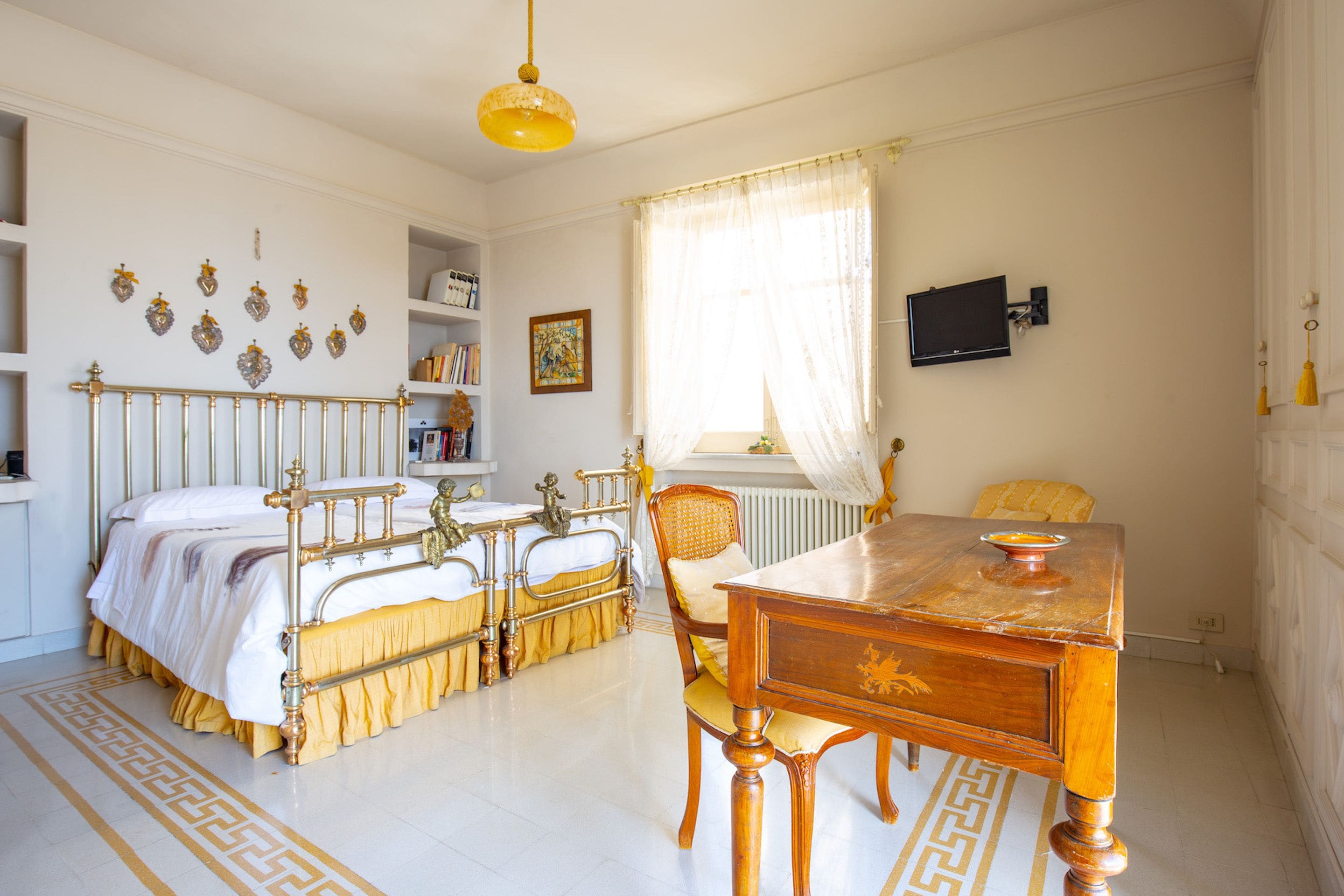 Een slaapkamer met een bed, nachtkastje, stoel en een bureau met een stoel.