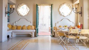 A room with a white sofa, a dining table with chairs, and a decorative mirror on the wall. - Solemar Sicilia - Casa Porto Bagnera (Santa Flavia)