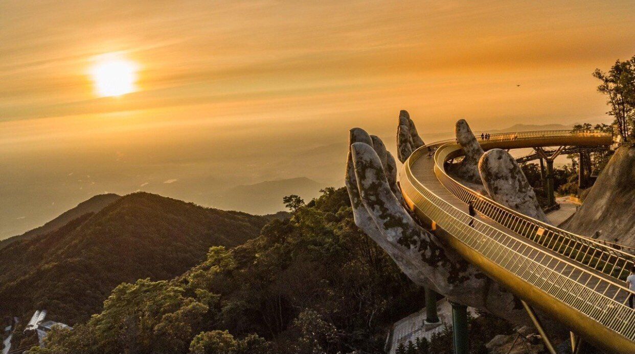 A suspension bridge with a unique design, surrounded by lush greenery and mountains.