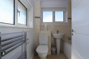 Ein kleines Badezimmer mit Toilette, Waschbecken und Badewanne.