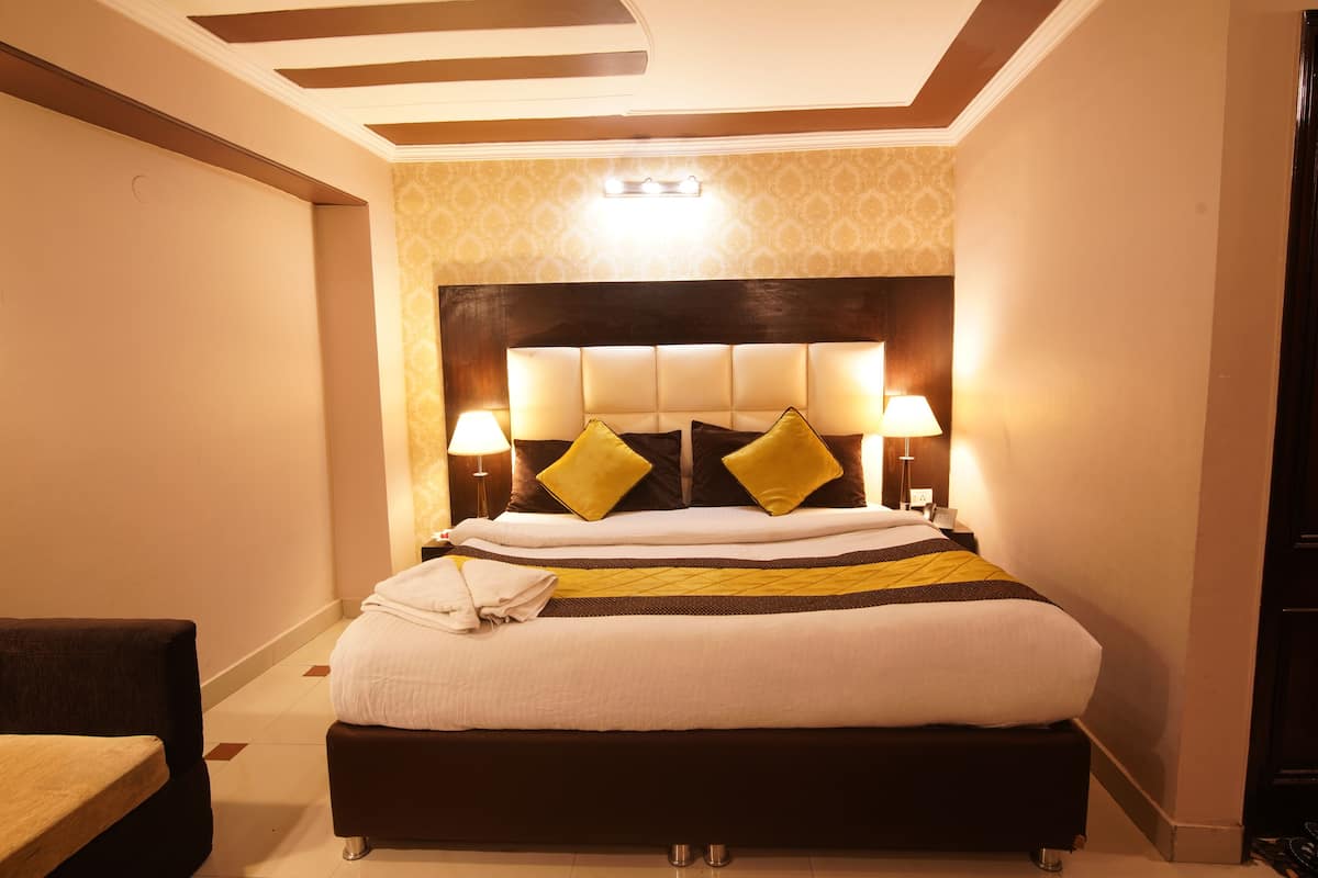 Habitació d'hotel amb un llit gran, dues làmpades laterals i un capçal de llit amb llum.