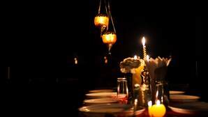 A dimly lit dining table with candles, plates, and a bottle, suggesting a romantic or intimate dining setting. - Ashirwad Hotel and Spa (Mussoorie)