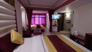 A hotel room with a large bed, a sofa, a television, and a small desk. - Ashirwad Hotel and Spa (Mussoorie)