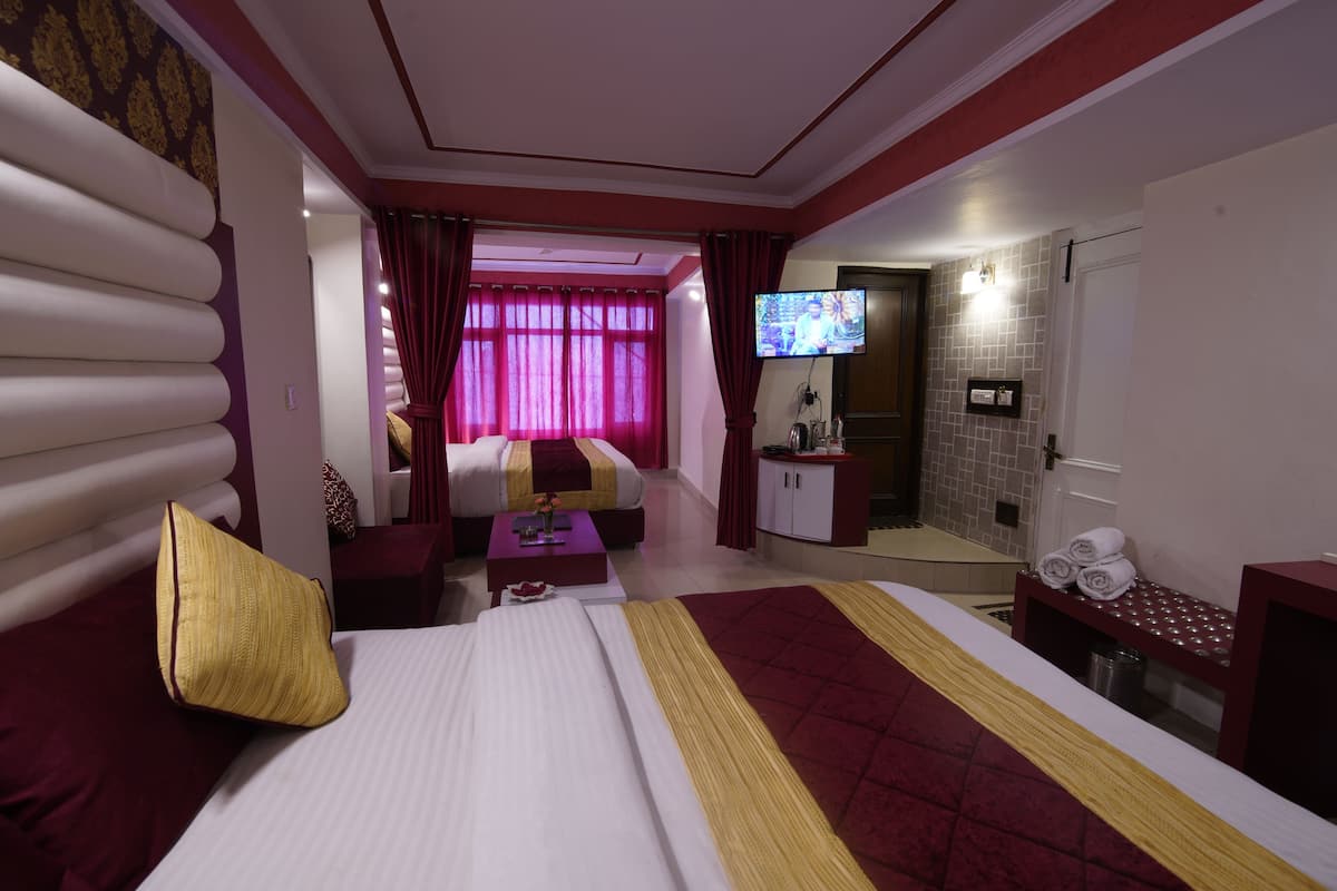 Habitació d'hotel amb un llit gran, un sofà, una televisió i un escriptori petit.