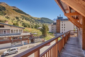 Bergblick von einem Holzbalkon mit Blick auf eine Stadt, im Hintergrund ein Restaurant und eine Seilbahn.