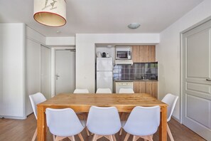 Une cuisine de taille réduite équipée d’un four à micro-ondes, d’un réfrigérateur et de meubles de rangement en bois.