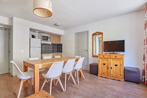 A compact living space with a dining area, kitchenette, and a television.